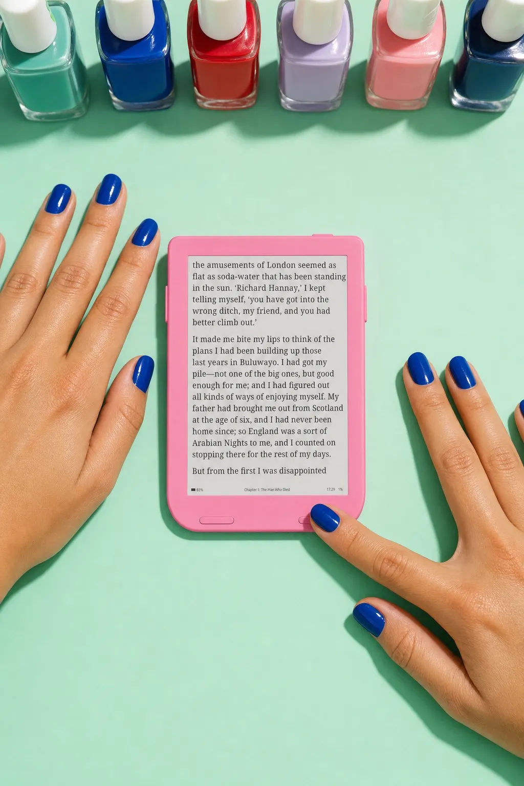 Turning the page on a pink Snug Mini while cobalt nail polish dries